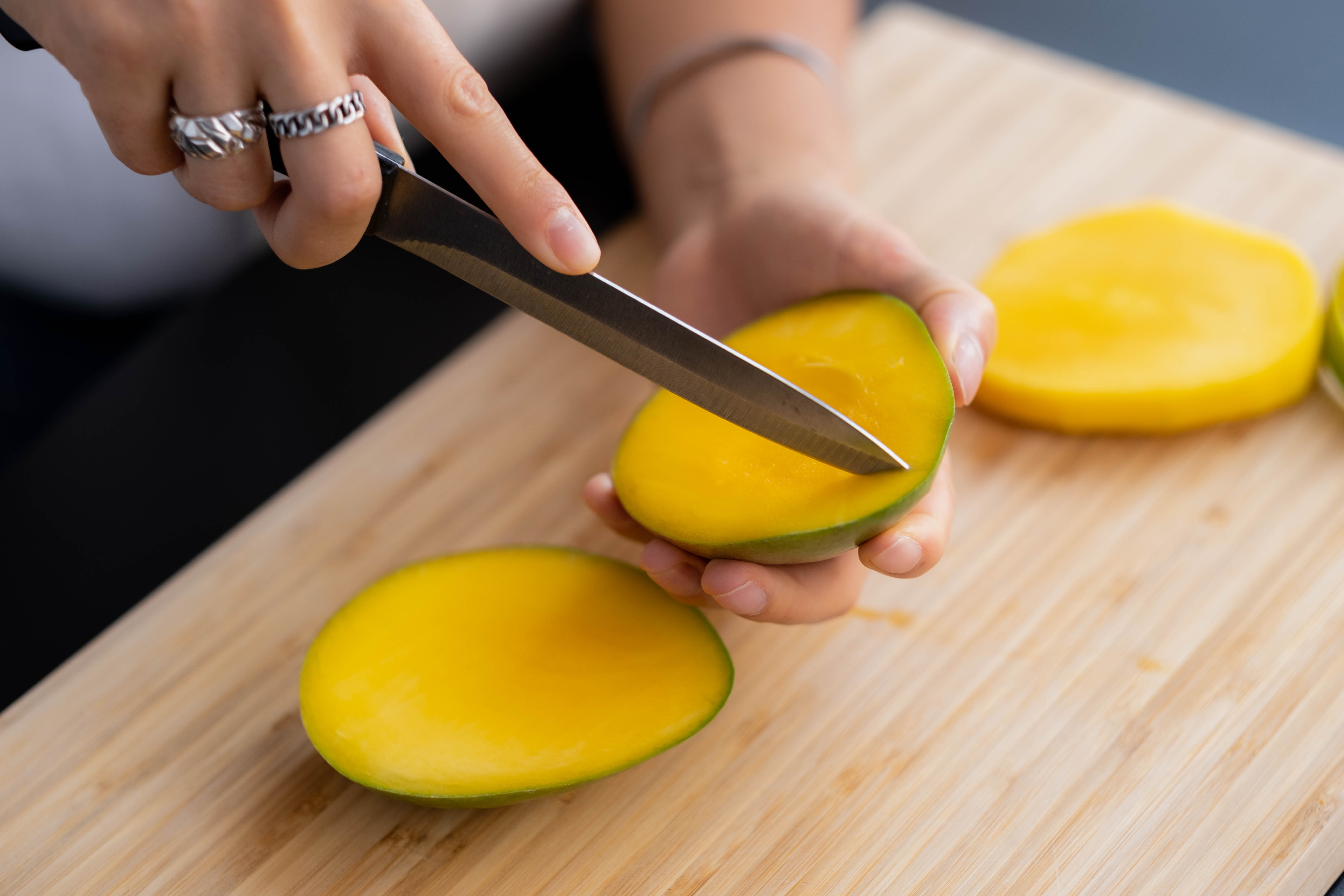 persoon snijdt mango