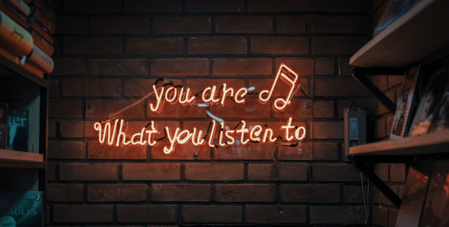 neon sign met "you are what you listen to"