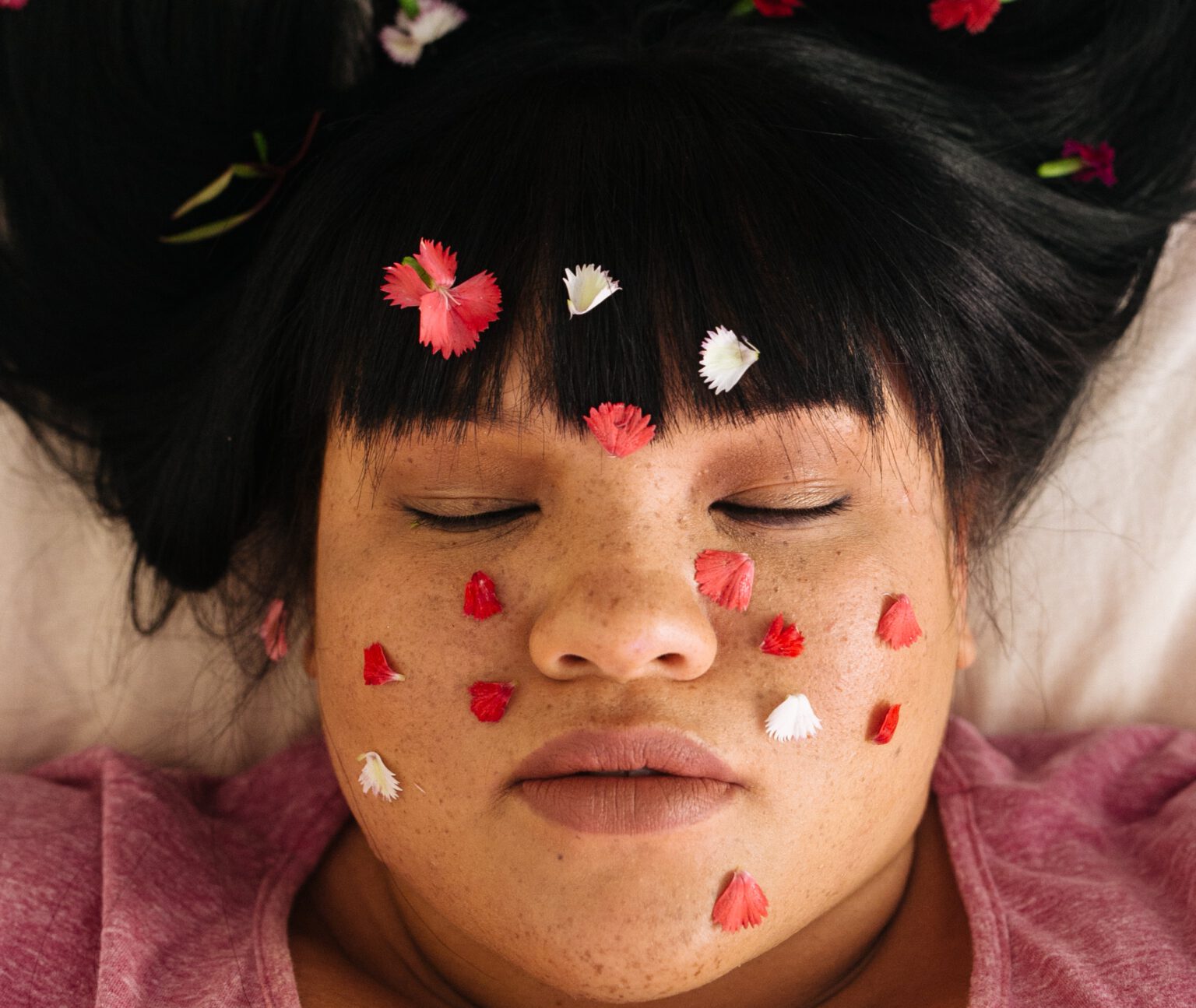 vrouw met rozenblaadjes op gezicht