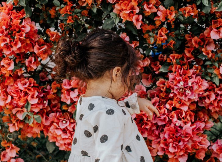 klein meisje voor een bloemenstruik