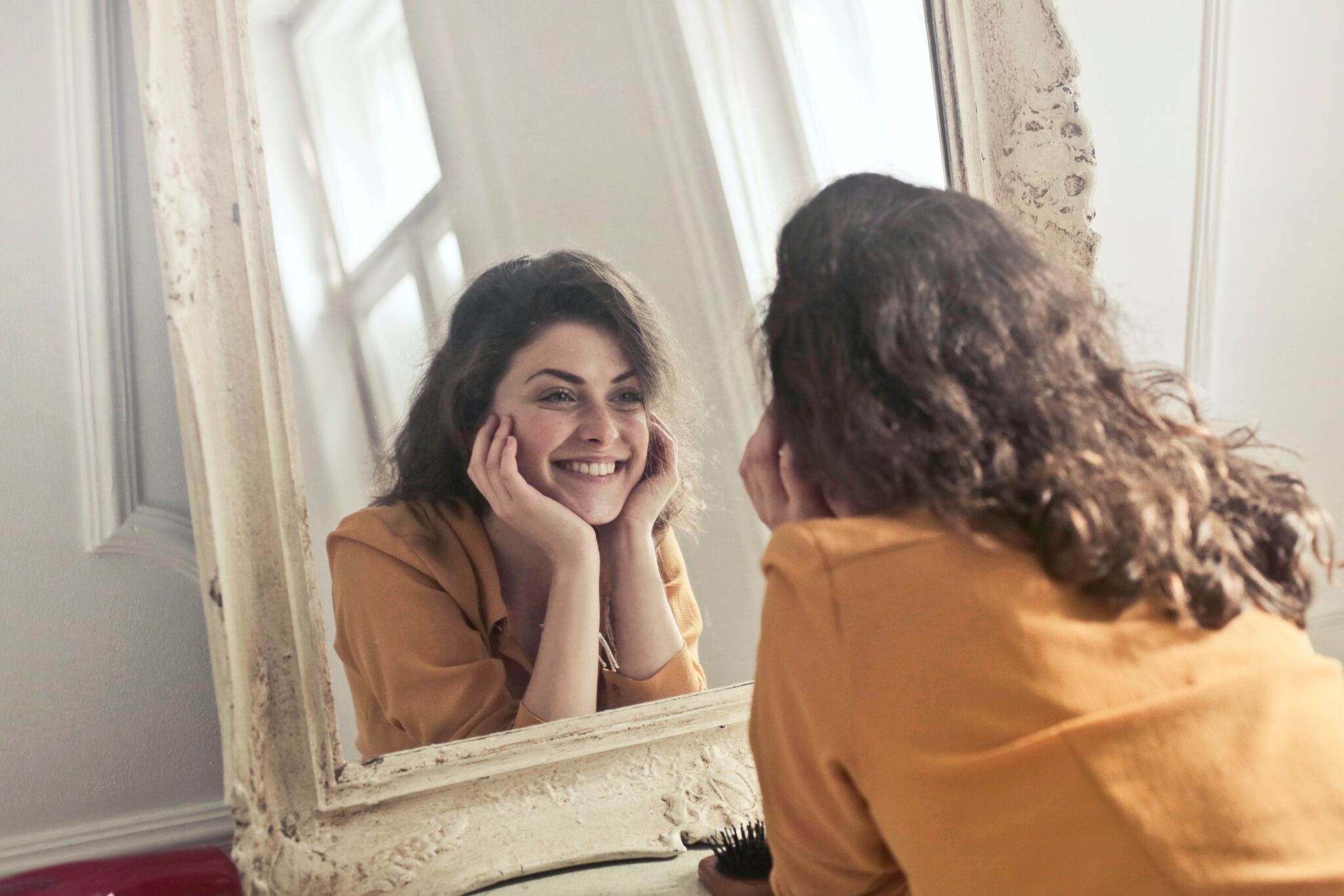 Vrouw die naar zichzelf kijkt in de spiegel