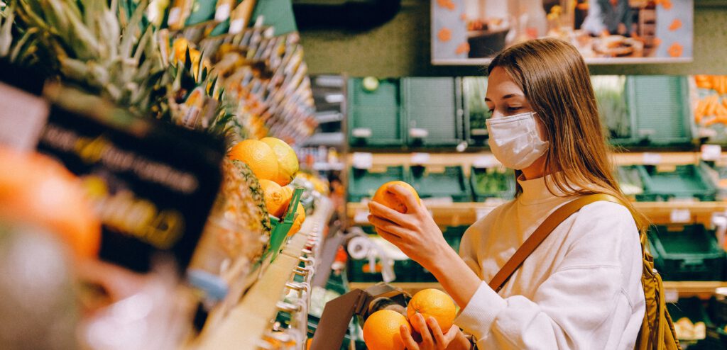 Vrouw met mondkapje in de supermarkt bij het fruit