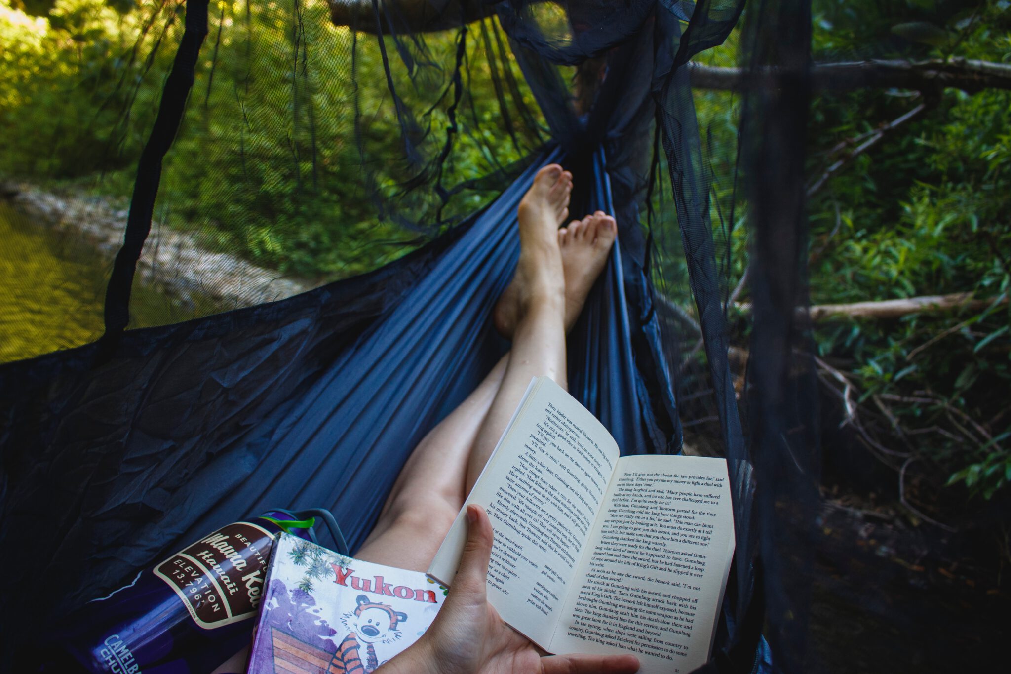 boeken over reisverhalen, persoon leest boek in hangmat in de natuur