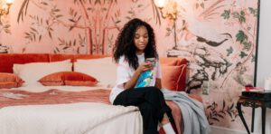 FOMO social media, persoon zit op bed en kijkt op telefoon