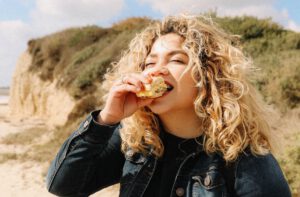 gezonde relatie met voeding, vrouw eet boterham op strand