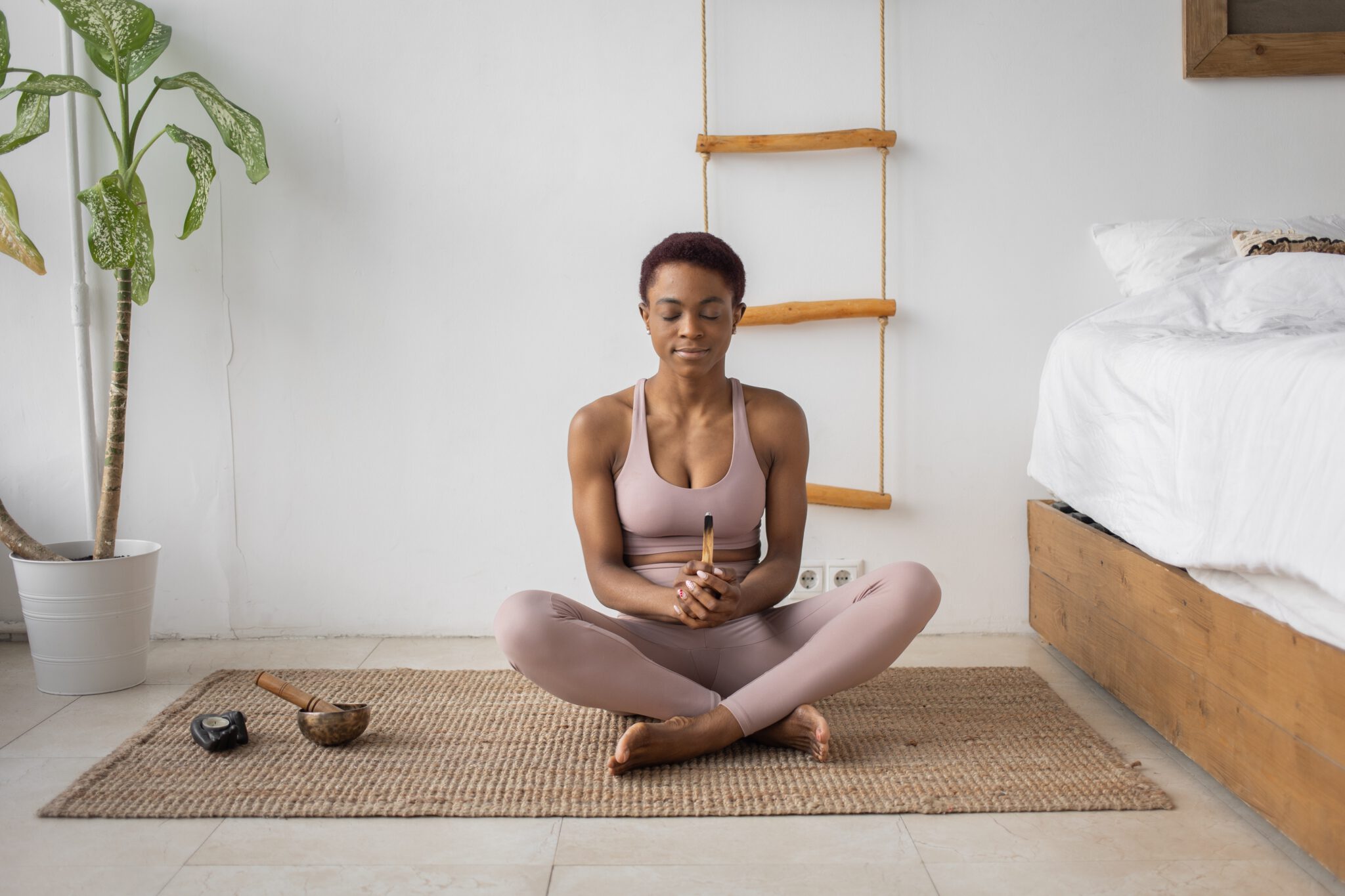 vrouw op yogamat en palo santo in haar hand