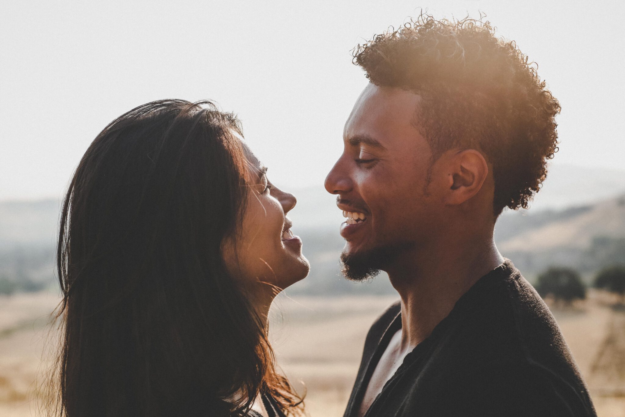 vrouw en man op het strand kijken elkaar verliefd in de ogen