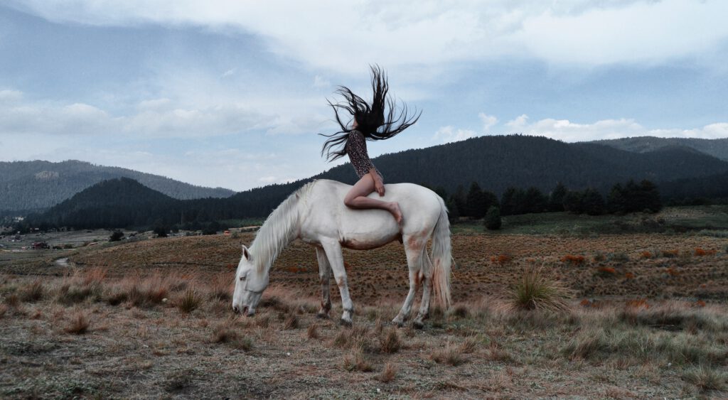 vrouw zit op paard en gooit haar haren los