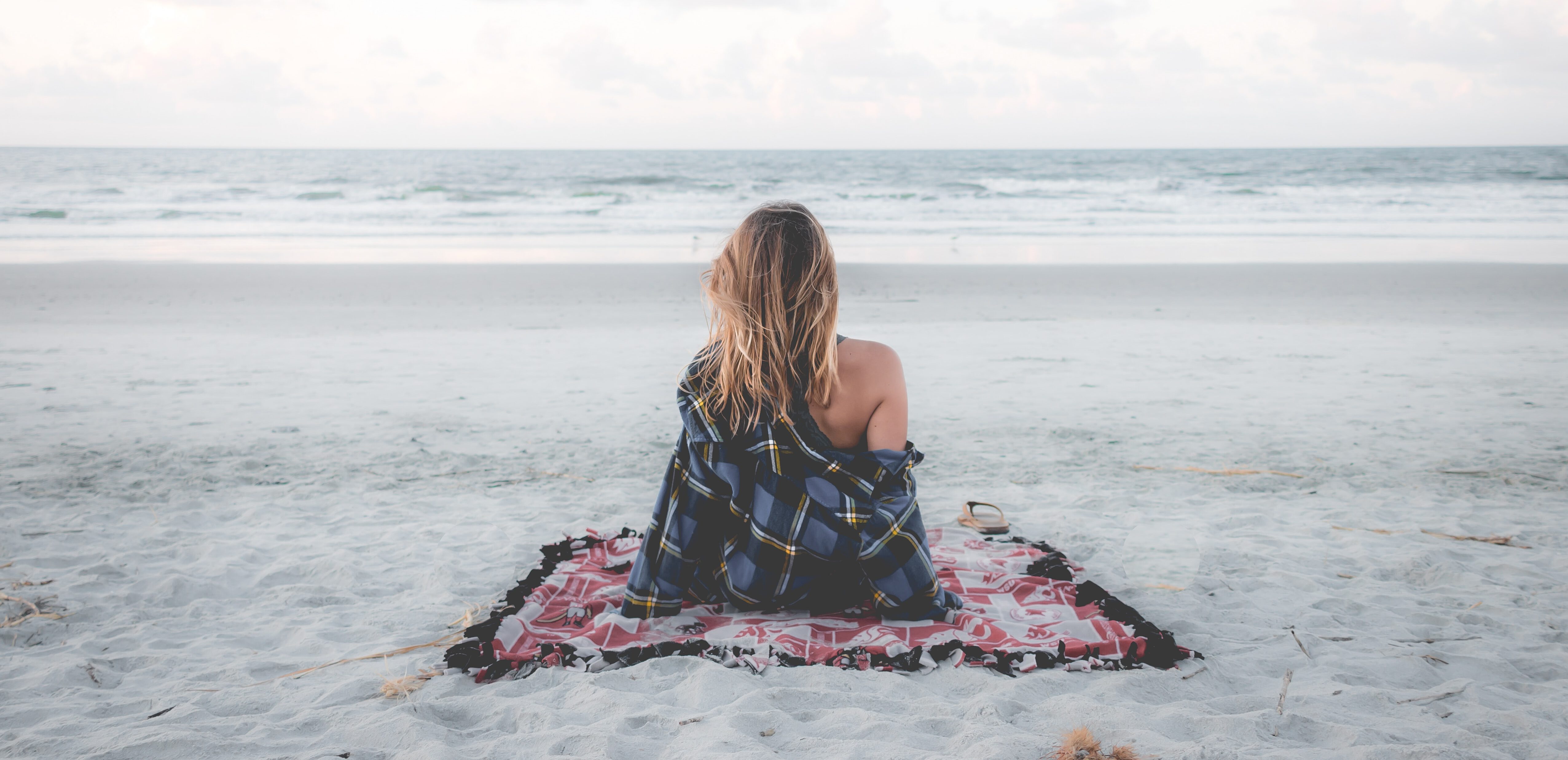 vrouw alleen op een kleedje op het strand